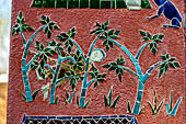Wat Xieng Thong temple in Luang Prabang, Laos.  La Chapelle Rouge , the Red Chapel. The exterior walls are decorated with colourful mosaics on a pink background with scenes of people daily activities. South wall. 